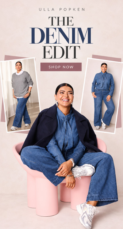 Γυναίκα με total denim look Ulla Popken, καθιστή σε ροζ πολυθρόνα